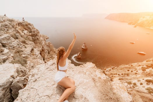 Woman travel sea. Happy tourist in hat enjoy taking picture outdoors for memories. Woman traveler posing on the beach at sea surrounded by volcanic mountains, sharing travel adventure journey