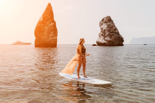 Close up shot of beautiful young caucasian woman with black hair and freckles looking at camera and smiling. Cute woman portrait in a pink bikini posing on a volcanic rock high above the sea