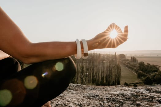 Well looking middle aged woman with long hair, fitness instructor in leggings and tops doing stretching and pilates on the rock near forest. Female fitness yoga routine concept. Healthy lifestyle.