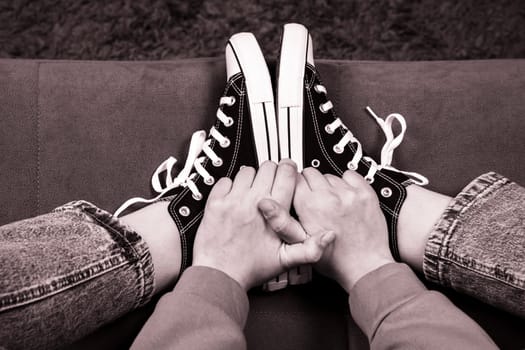 the girl's legs shod in classic sneakers. A sneakers on a girl's leg. Teenager's feet in casual new sneakers on the sofa close up image. Vintage style. concept image
