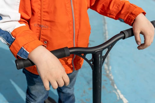 rider's hands are on the handle bar of the stunt scooter. Time to ride and have fun. a child or a guy rides a scooter during the holidays or on weekends in a skate park. Extreme sports