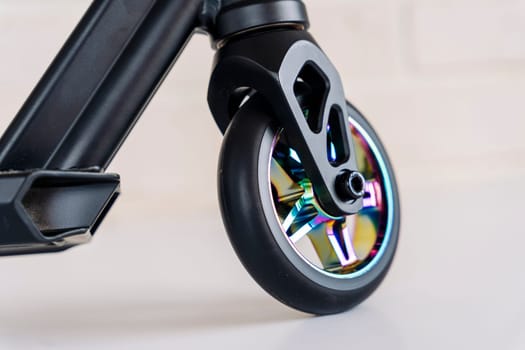 The front wheel of a rainbow-colored stunt scooter or a durable children's stunt scooter with rubber wheels for extreme skating in a skatepark and on a ramp. Scooter Details