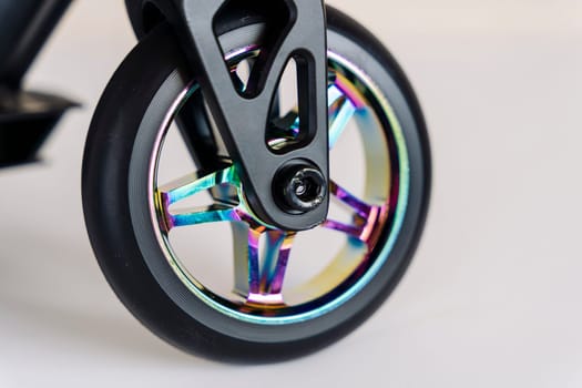 The front wheel of a rainbow-colored stunt scooter or a durable children's stunt scooter with rubber wheels for extreme skating in a skatepark and on a ramp. Scooter Details