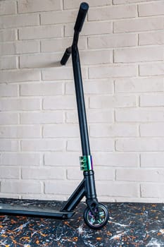 The front wheel of a rainbow-colored stunt scooter or a durable children's stunt scooter with rubber wheels for extreme skating in a skatepark and on a ramp. Scooter Details. vertical photo