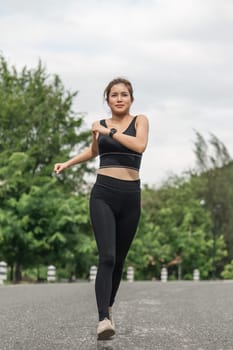 Young smiling sporty woman running in park in the morning. Fitness girl jogging in park.