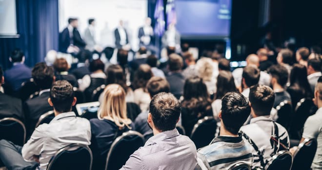 Speaker giving a talk in conference hall at business event. Rear view of unrecognizable people in audience at the conference hall. Business and entrepreneurship concept