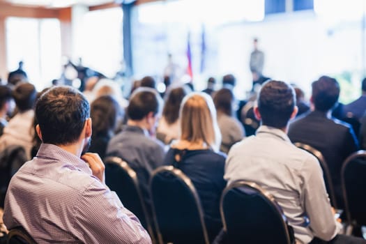 Speaker giving a talk in conference hall at business event. Rear view of unrecognizable people in audience at the conference hall. Business and entrepreneurship concept