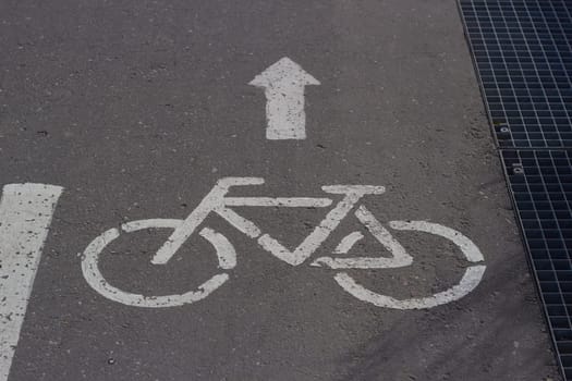 Photo sign on pavement bicycle with white paint arrow. Road traffic. Urban transport. Cyclists. Road marking.