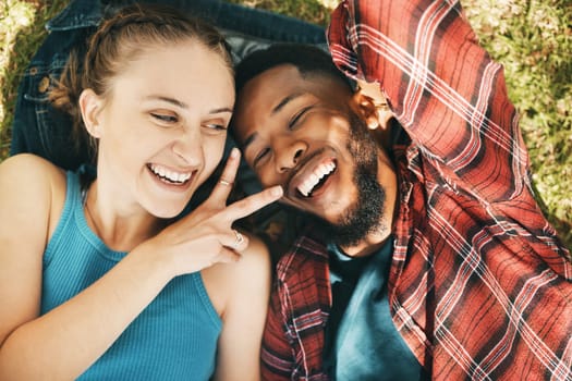 Interracial couple, park selfie and peace on grass with love, happiness and relax on holiday. Black man, woman and profile picture on lawn for social network app with romance, funny and comic time.