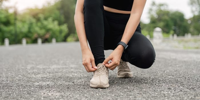 Portrait of a happy active beautiful woman posing fixing shoelace on her running shoe after exercising outdoors.