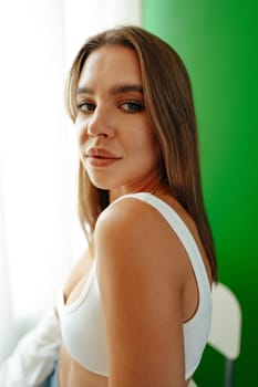 Portrait of attractive lovely girl wearing crop top and shirt posing over green studio background close up