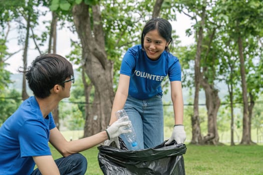 Cropped view of young volunteers collecting trash in the park. Trash bins in the park. Ecology group. Environmental protection concept. Team with recycling project outside.