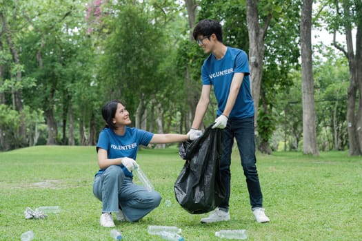 Cropped view of young volunteers collecting trash in the park. Trash bins in the park. Ecology group. Environmental protection concept. Team with recycling project outside.