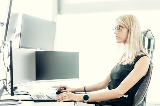 Female financial assets manager, trading online, watching charts and data analyses on multiple computer screens. Modern corporate business woman concept.