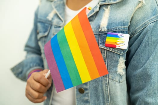 Woman holding LGBT rainbow colorful flag, symbol of lesbian, gay, bisexual, transgender, human rights, tolerance and peace.