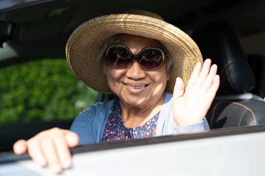 Asian elderly woman with hat sitting in car with enjoy and freedom in traveling trip.