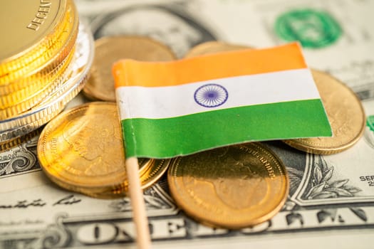 Stack of coins with India flag and US dollar banknotes.