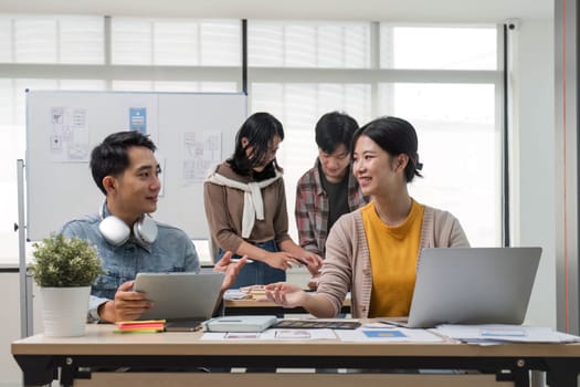 A group of professional Asian UI, UX graphic designers, or developers is in the meeting, brainstorming and planning a new project together...