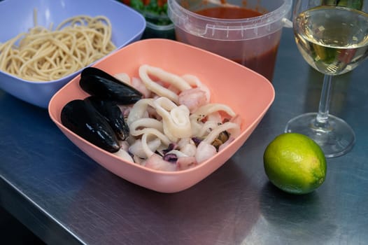 Raw ingredients for cooking seafood pasta -spaghetti, mussels, sauce, lime, tomato and white wine