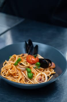 Seafood Pasta with mussels with basil and tomato in black plate