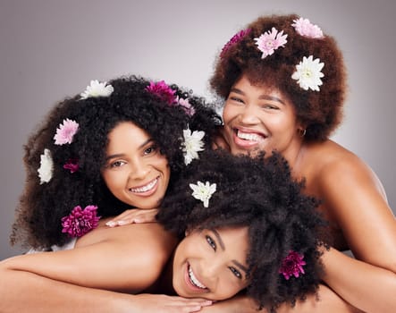 Friends, hair care and portrait of black women with flowers in studio isolated on a gray background. Floral cosmetics, organic makeup and face of group of girls with flower for beauty and aesthetic