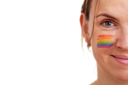 Portrait of a young smiling woman with LGBT flag painted on her cheek. Theme of equality and freedom of choice.