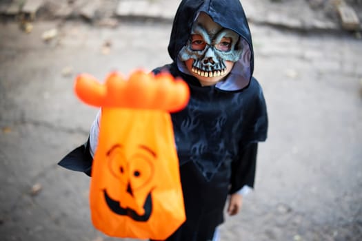 Little boy in halloween costume and mask holding a special candy bag in his hand. Trick or treat.