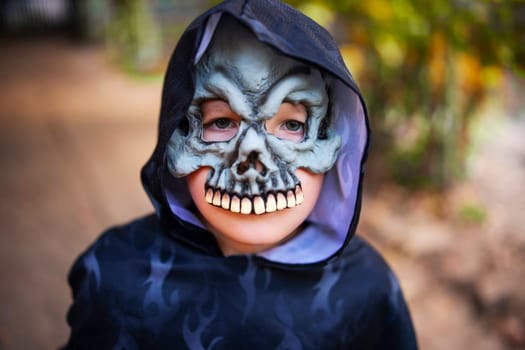 Portrait of a little boy in a halloween costume and mask outdoor. Trick or treat.