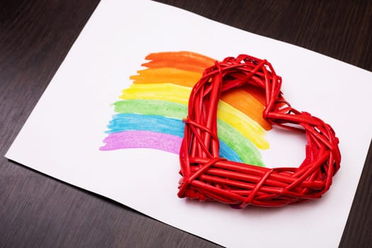 Painted rainbow on a white sheet of paper with red heart on wooden background. LGBT (Lesbian, Gay, Bisexual, Transgender) human rights and freedom concept.