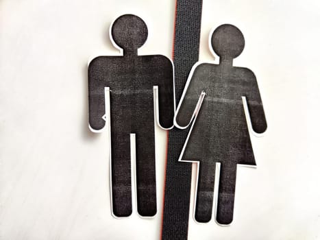 The concept of divorce, quarrels, and separation of a couple. Paper black figurines of a man and a woman separated by black line. Abstract background, texture