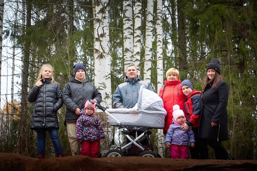 Kirov, Russia - October 23, 2022: Big family with parents, mom and dad, with children, toddlers, teenagers walking in park on an autumn day with yellow trees and leaves