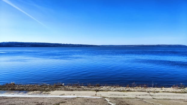 Beautiful blue water, sky and earth on the distant horizon. Natural landscape with water on sunny day. Background with landscape and copy space