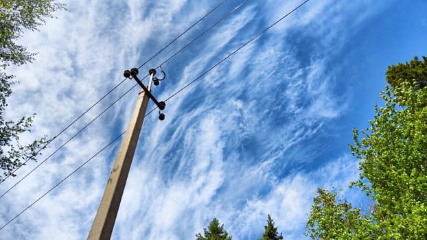 Closeup of old power poles on clear summer day. Old hight voltage electric pole with wires and blue sky with clouuds on background