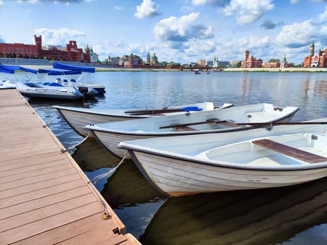 Harbor with wooden boats in city. Embankment of the resort town. Sunny summer day and water landscape in summer