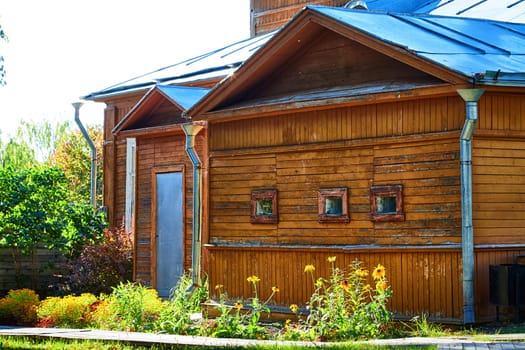 An old wooden rural house in countryside village on a sunny summer or spring day and greenery with trees and grass arround