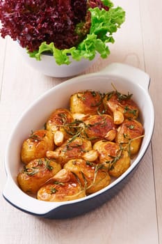 Roasted potatoes with garlic, thyme and rosemary in ceramic baking dish
