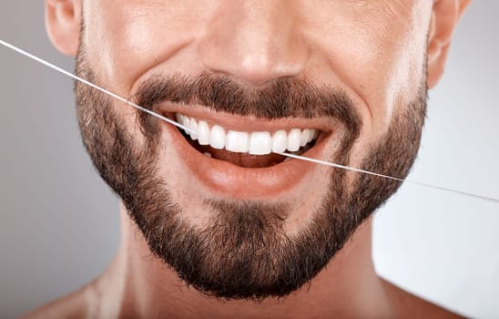 Dentist, floss and mouth of man with smile on gray background in studio for wellness, healthcare and hygiene. Dental care, grooming and zoom of male model for dentistry, cleaning and flossing teeth.