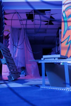 Neglected building filled with fluorescent bright lights, urban space displaying graffiti spray paint and purple neon light. Empty deserted warehouse being illuminated and grungy.