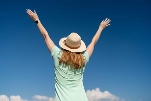 Woman Tourist Sky. Happy traveller woman in hat enjoys vacation raised her hands up.