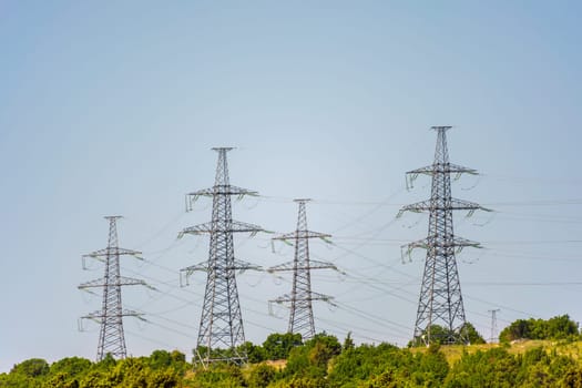 High voltage towers with sky background. Power line support with wires for electricity transmission. High voltage grid tower with wire cable at distribution station. Energy industry, energy saving.