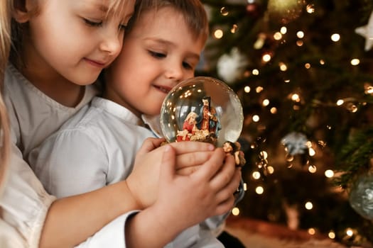 The kids looking at a glass ball with a nativity scene of the birth of Jesus Christ
