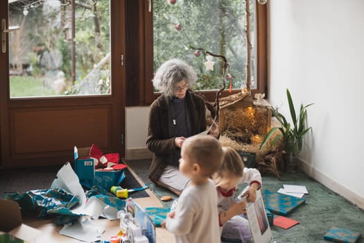 Grandmother and grandchildren open gifts for Christmas