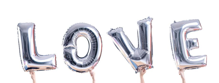 Foil silver color balloons in LOVE word held on woman's hand isolated on white background.