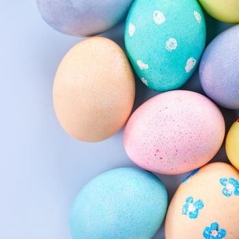 Colorful Easter eggs dyed by colored water with beautiful pattern on a pale blue background, design concept of holiday activity, top view, copy space.