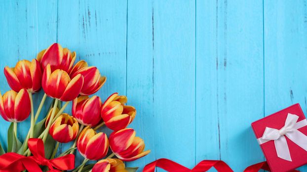 Tulip flower bunch, Mother's Day Design Concept - Beautiful Red, yellow bouquet isolated on blue wooden background, top view, flat lay, copy space