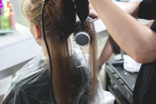 Close up of hairdressers hands drying long blond hair with blow dryer