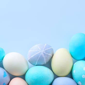 Colorful Easter hunting eggs dyed by colored water with beautiful pattern on pastel blue background, design concept of holiday, top view, copy space.