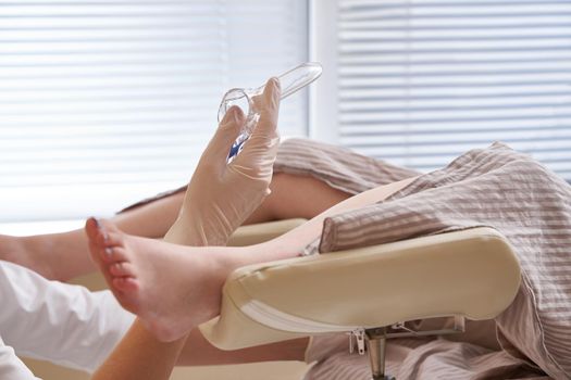Woman gynecologist examining patient using mirror in clinic