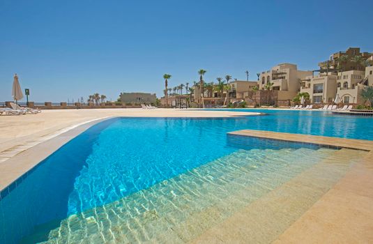 Large outdoor swimming pool at a luxury tropical hotel resort with steps