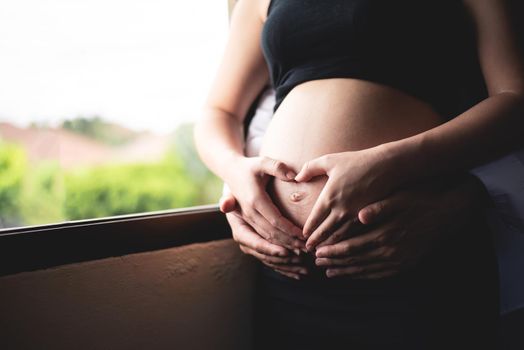 beautiful pregnant woman and her handsome husband hugging the tummy